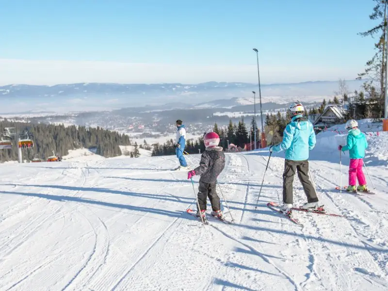 Children with parents learning to ski on the slope